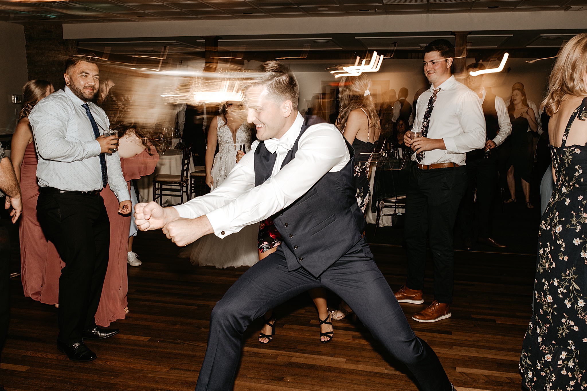 Groom dancing on reception dancefloor with shutter drag behind him.