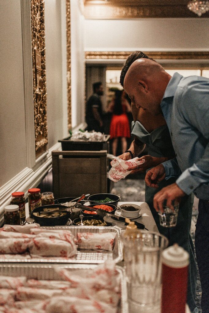 Couple putting together toppings on a hot dog at wedding reception.