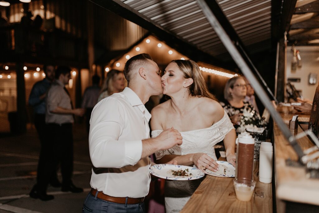 Bride and Groom kissing by a taco truck at their wedding.