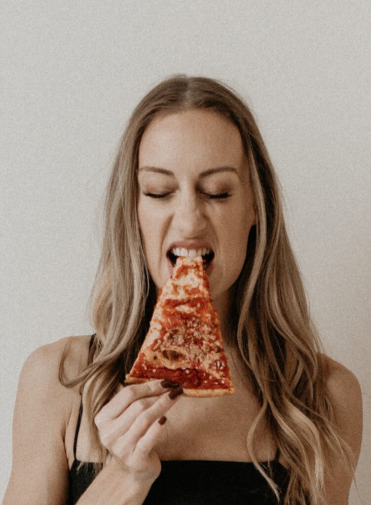 Girl eating a slice of pizza, zoomed in close to the bite.