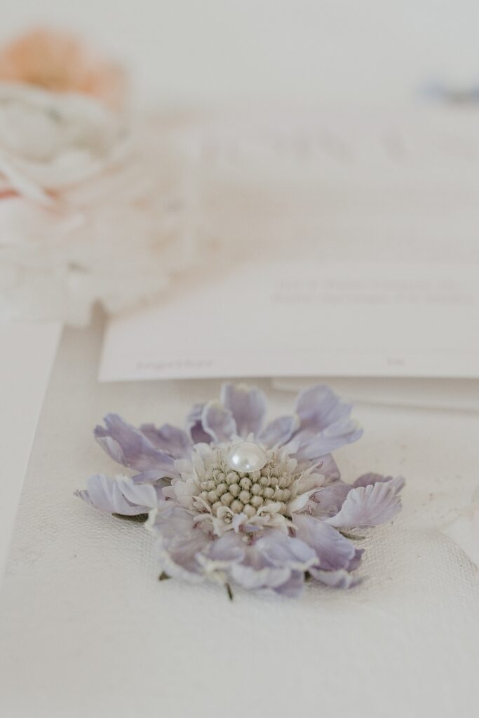 Purple flower with wedding invitation on flat lay mat