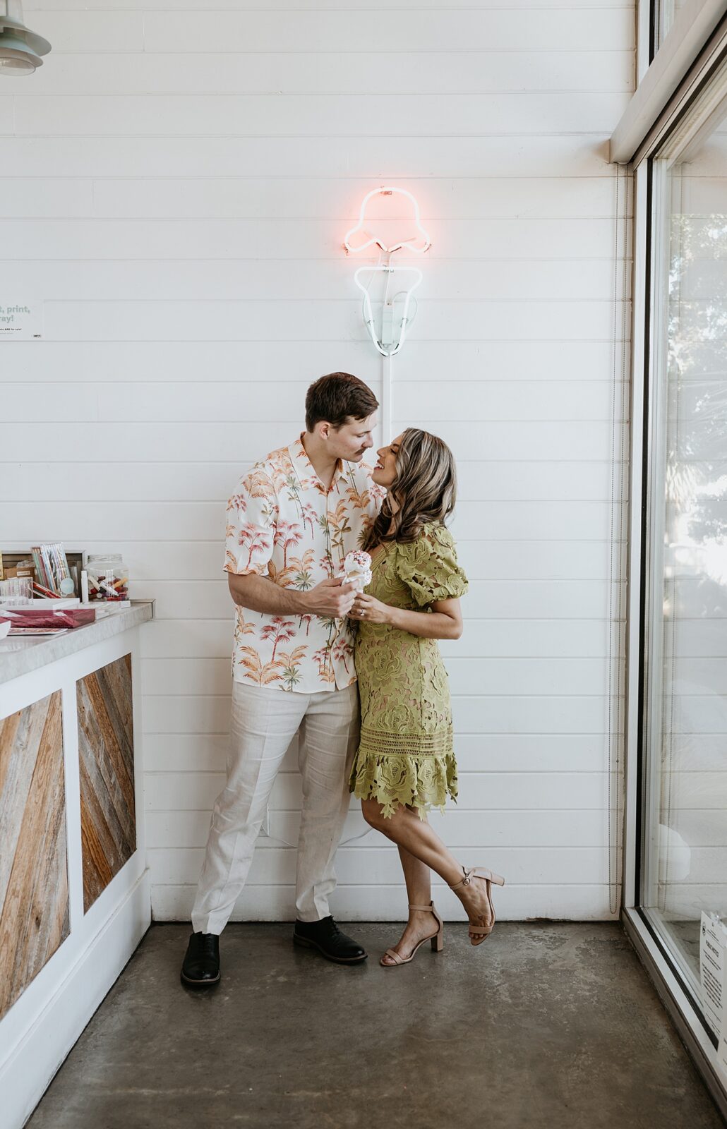 Couple having ice cream cone together with neon ice cream sign behind them