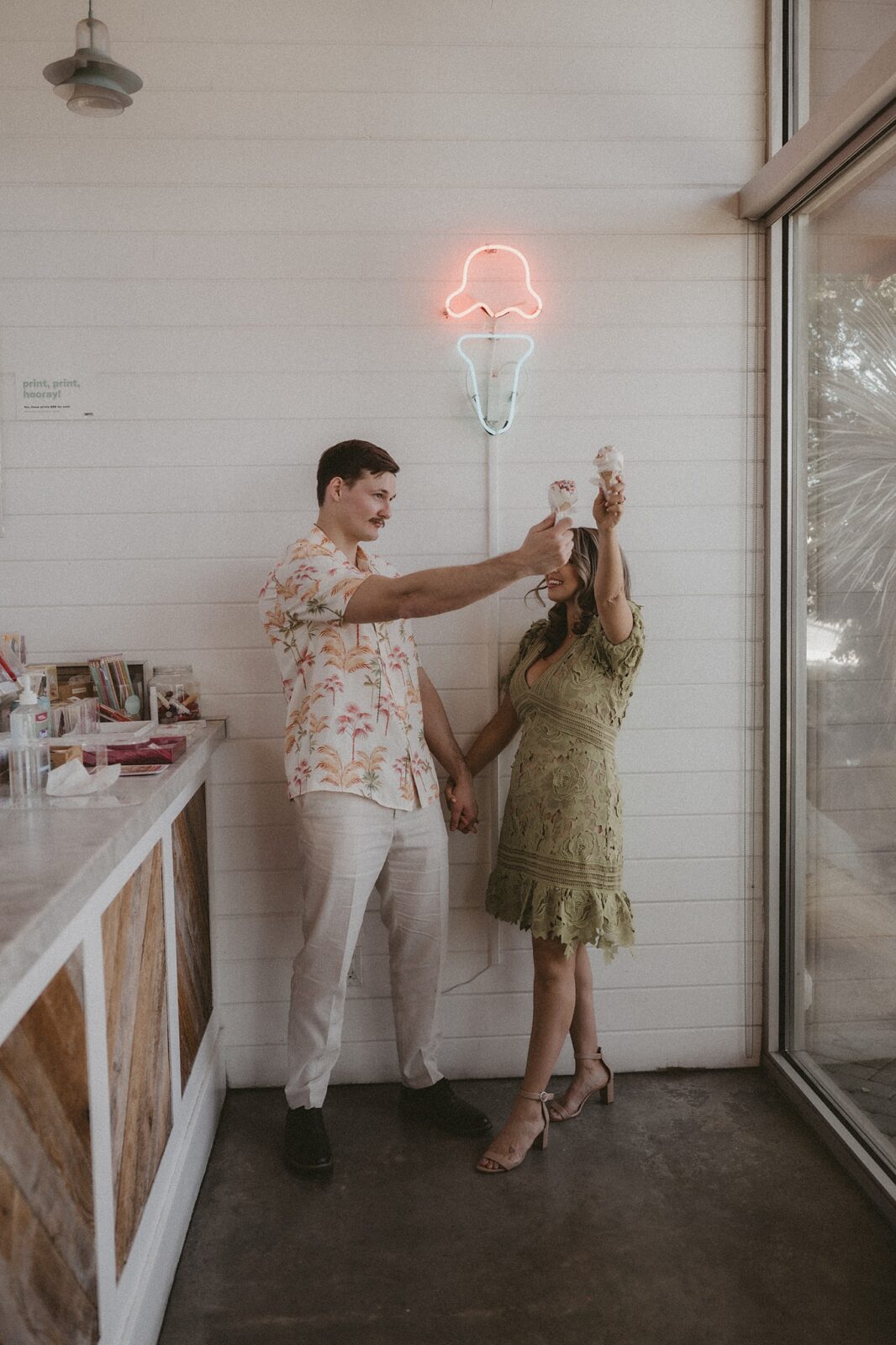 Couple is holding up their ice cream cones cheersing