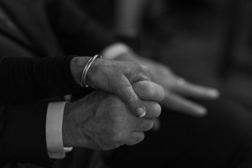 Close up of hands held in support, illustrating timeless monochrome wedding photography and the soul of the frame.