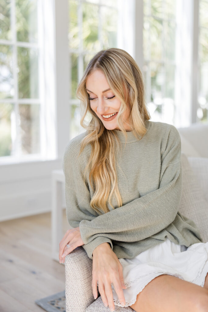 A creative business owner smiling warmly in a bright studio, illustrating how to maintain a joyful creative business vision.