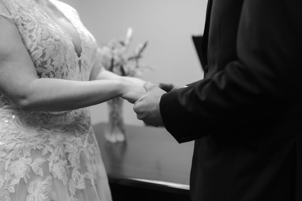 A close-up black and white photo of a couple holding hands, highlighting courthouse wedding tips for a quiet and intimate ceremony.
