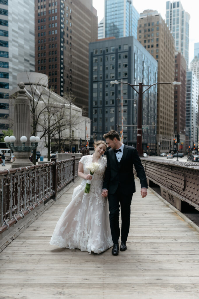 A bride and groom walking across a Chicago bridge, illustrating courthouse wedding tips for using the city as an urban photo studio.