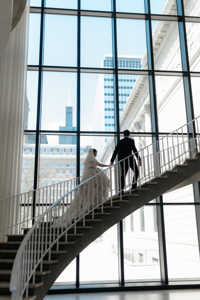 A bride and groom walking up stairs against a city skyline, following courthouse wedding tips for an intentional Chicago elopement.