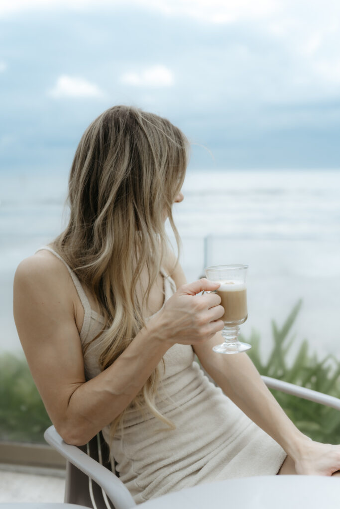 A business founder taking a quiet break by the water with a latte, showing how to step away and nourish a creative business vision.