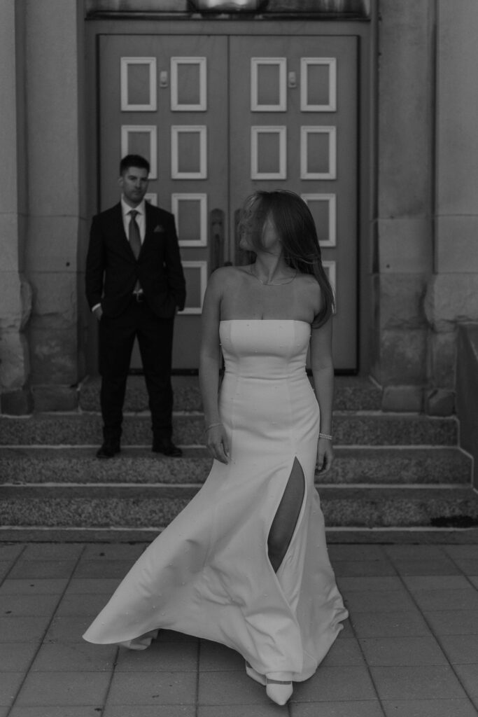 A couple stands near a historic building entrance, utilizing clean lines for cinematic wedding photos.