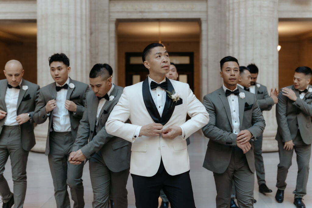 Groomsmen adjusting their jackets and bow ties before a city wedding ceremony.