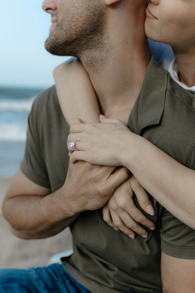 A close up portrait showing a woman wrapped around a man showing an engagement ring for fun engagement photo ideas.