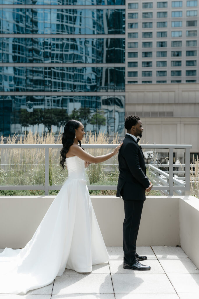 A bride about to surprise her groom during a rooftop first look portrait session.