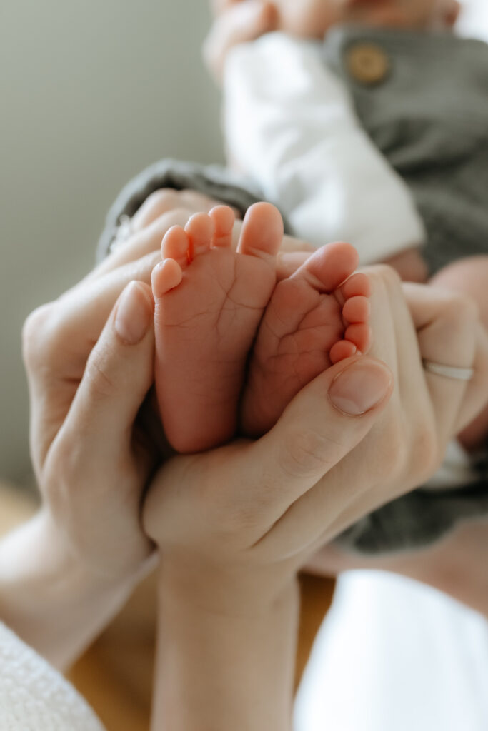 Close-up macro shot of parents gently cradling their tiny newborn's feet in their hands.