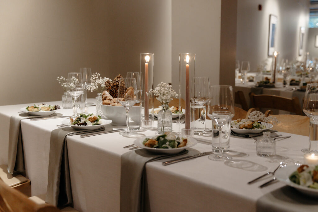 Candlelit reception table set with white linens, wine glasses, and delicate floral centerpieces before guests arrive.