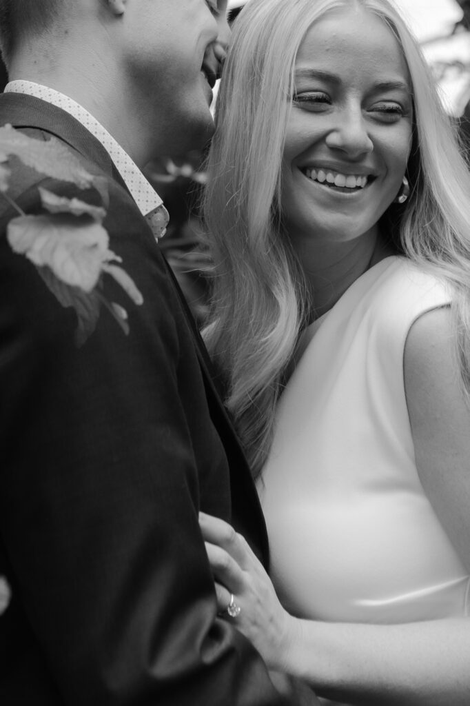 Black and white close-up shot of a blonde bride smiling happily next to her groom.